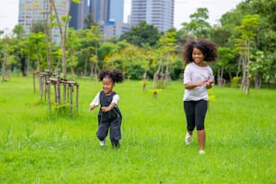 Happy mixed race family in park. Two Adorable little sibling sister running and playing together in public park. Adorable child girl kid enjoy and having fun outdoor lifestyle activity vacation.