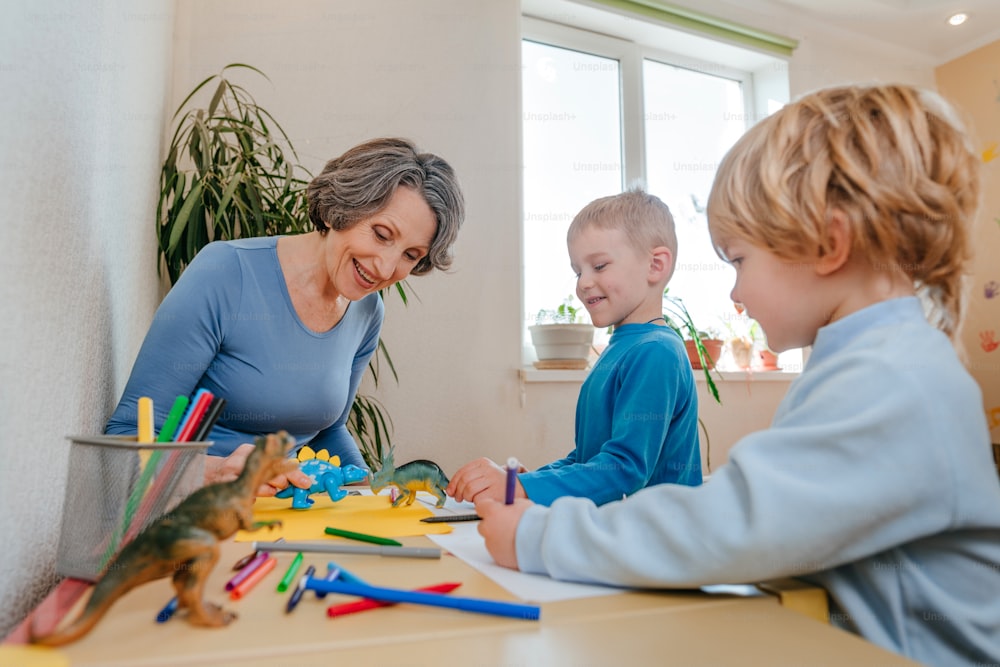 Niños jugando con su abuela con juguetes de dinosaurios en la habitación de los niños. Enfoque selectivo.