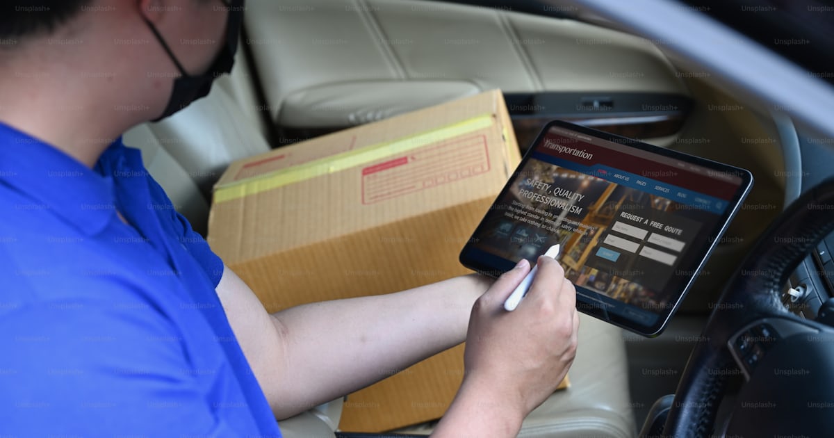 Delivery man driver using digital tablet while sitting in van with ...