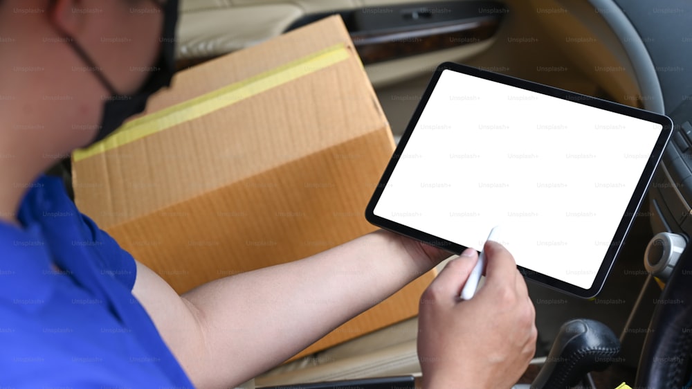 Nahansicht Zusteller mit digitalem Tablet während des Sitzens im Van. Lieferservice und Versandkonzept.