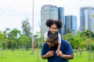 Happy mixed race family in park. African father carrying little daughter walking in the garden. Dad and child girl kid enjoy and having fun together outdoor lifestyle activity weekend vacation in summer