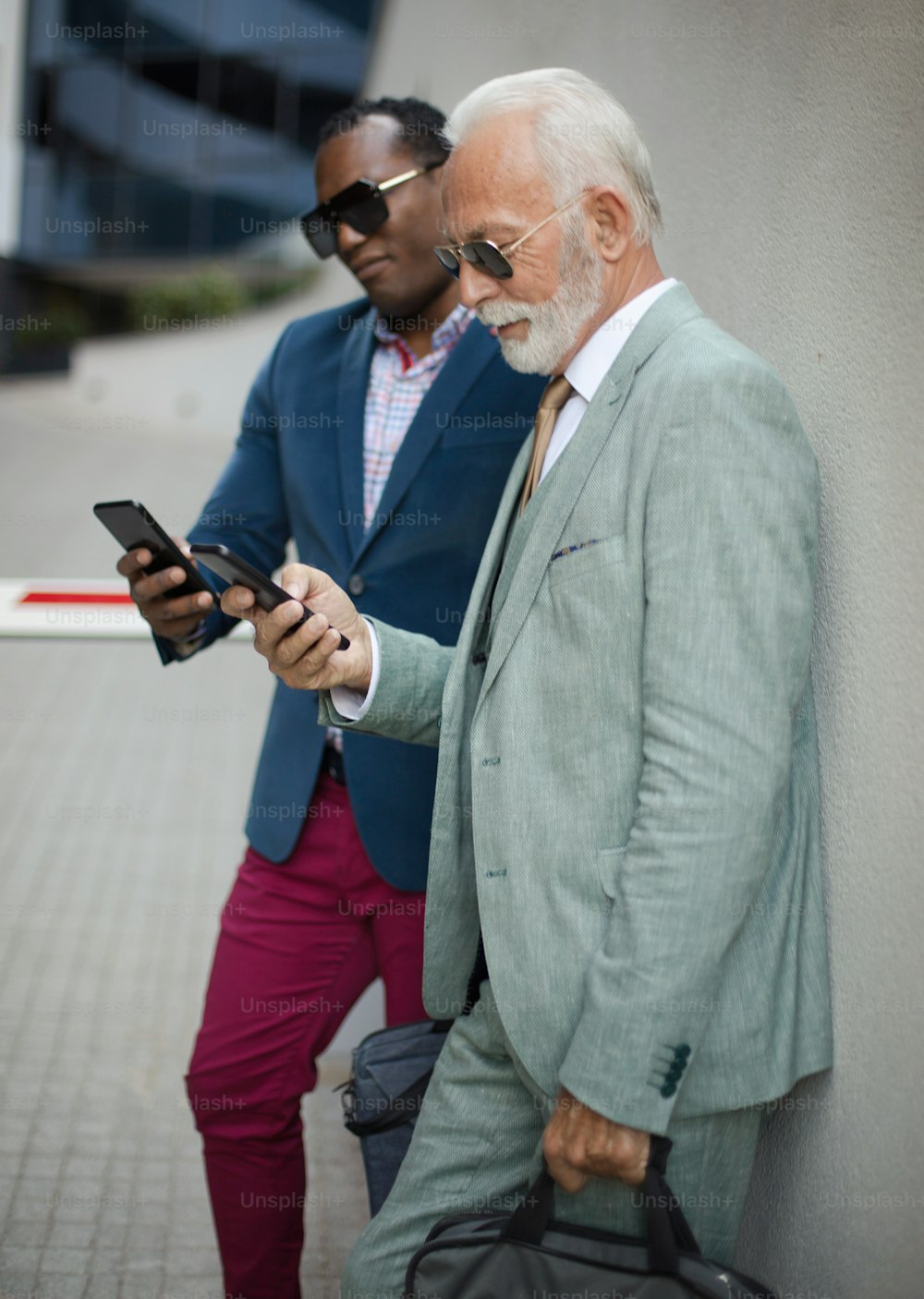 Dos hombres de negocios que usan el móvil al aire libre.