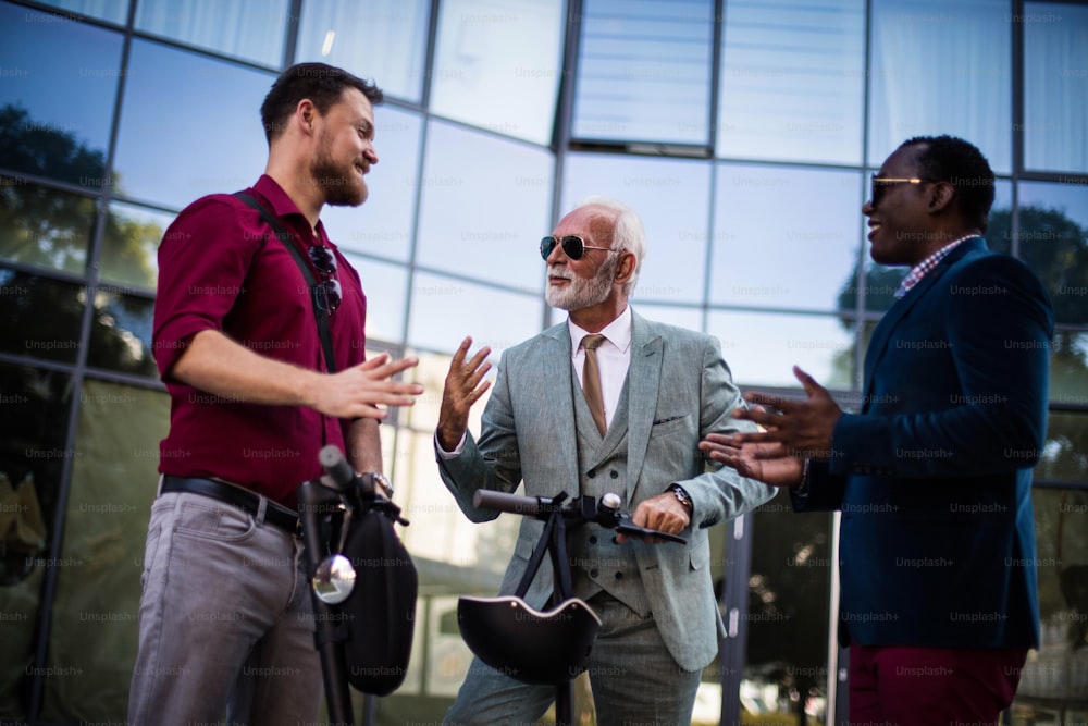 Small Group of smiling business men talking on the street. Focus is on senior man.