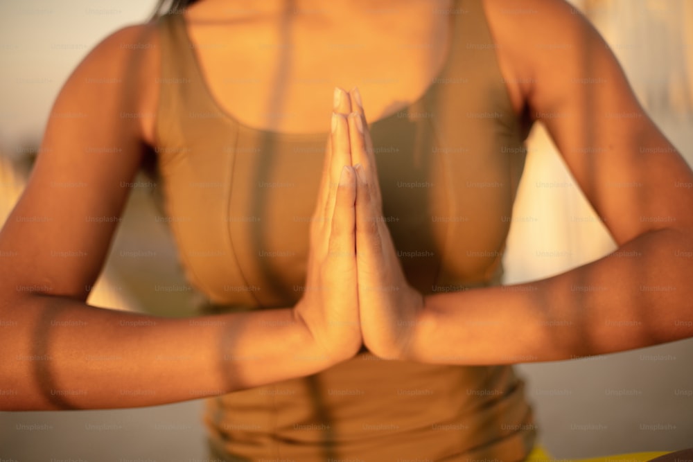 Mulher africana que trabalha yoga. De perto. O foco está nas mãos.