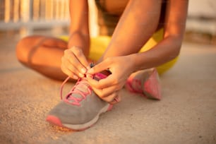 Unrecognizable Fit African Sportswoman Tying Shoelaces on Sneakers. Close up.