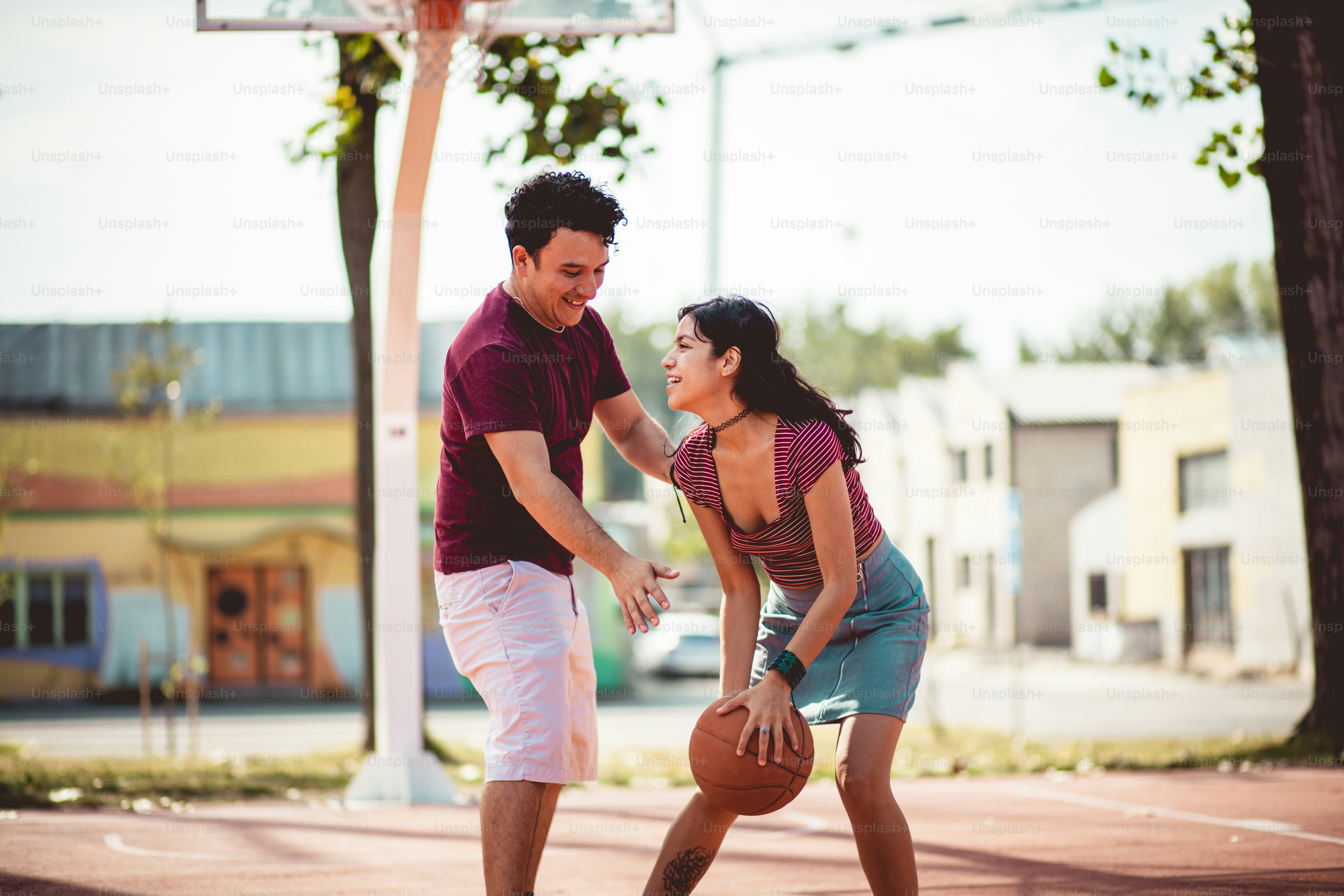 Pasangan muda yang bahagia bermain bola basket.