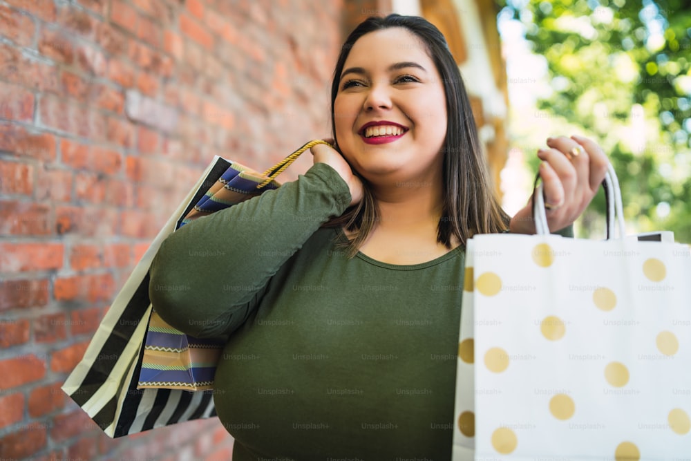 Portrait of young plus size woman holding shopping bags outdoors on the street. Shopping and sale concept.