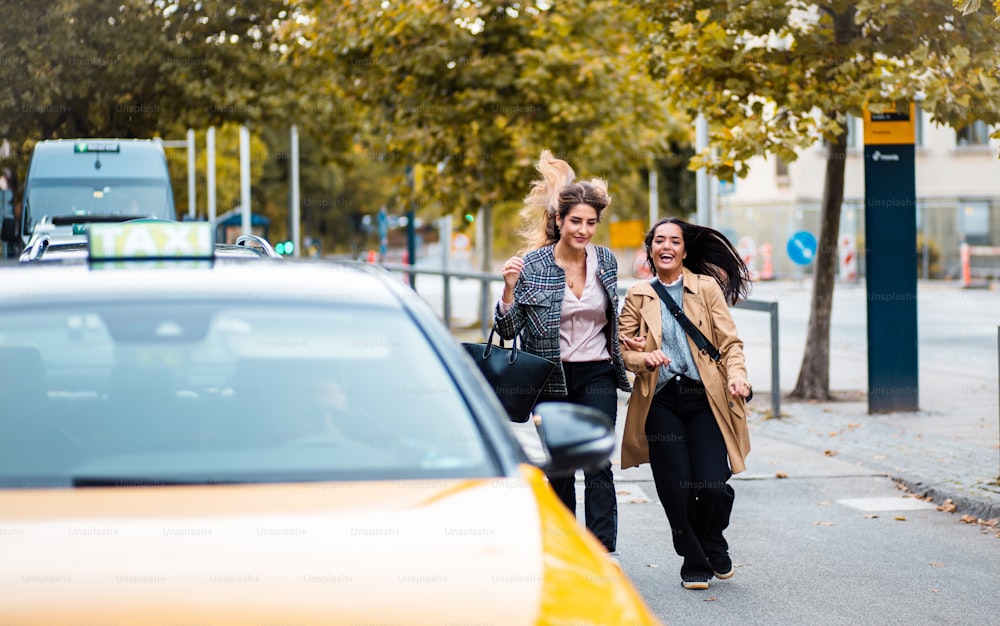 Duas mulheres sorridentes correm para o táxi.