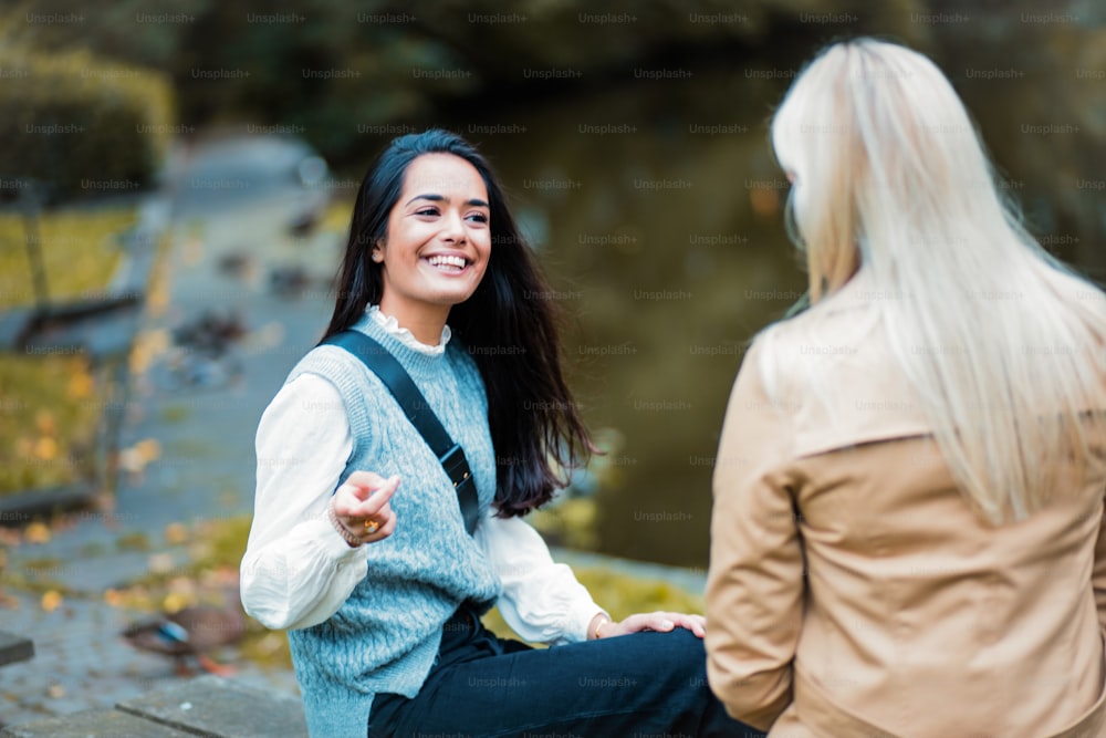 Two women having conversation in the park. Focus is on smiling woman.