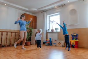 Active grandmother playing the ball with her grandchildren in the kids room indoor. Selective focus.