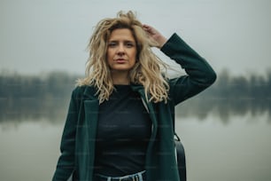 Portrait of a beautiful blonde woman posing in the nature wearing a green coat