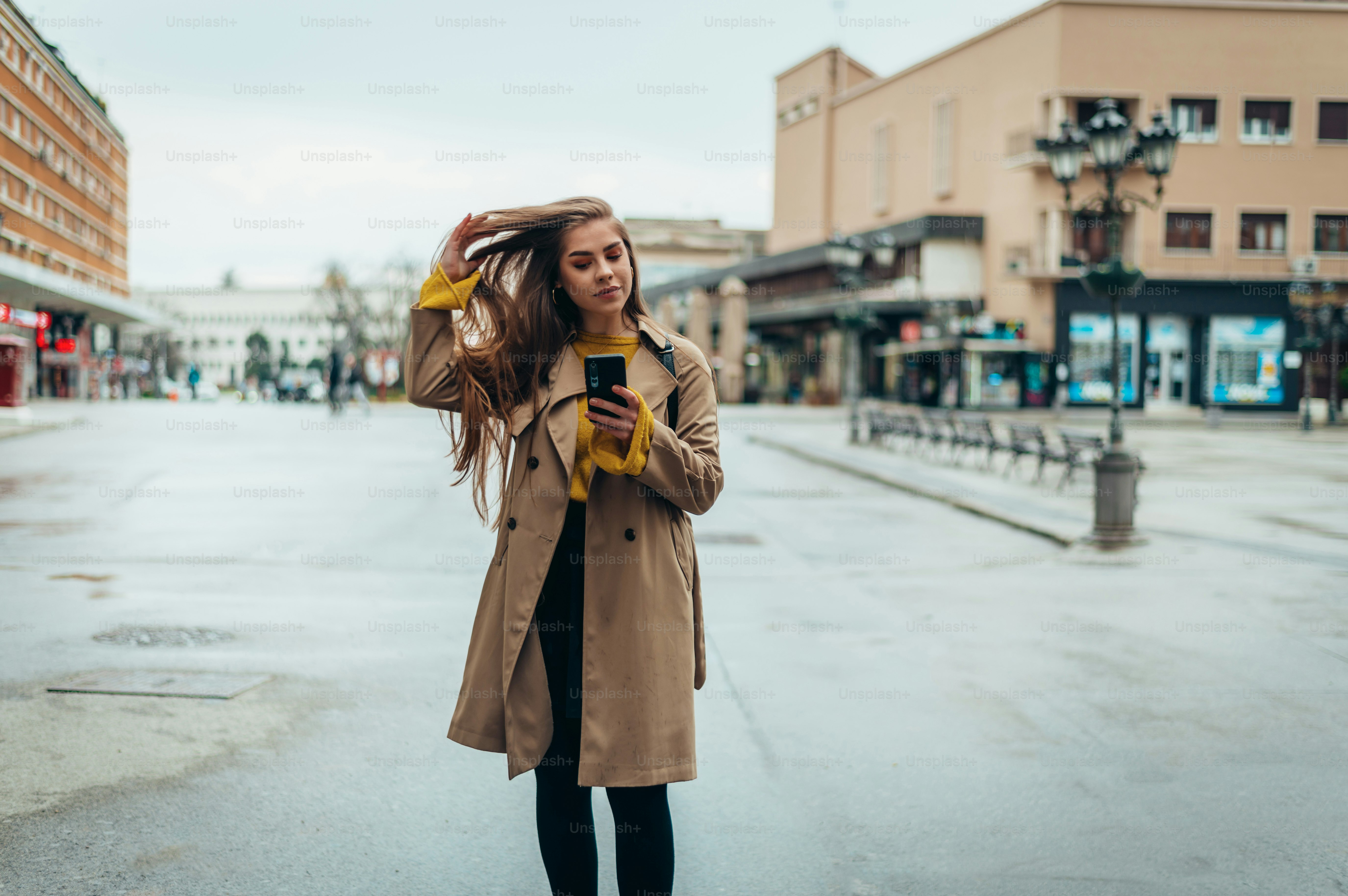 Young beautiful woman using a smartphone while out in the city walking ...