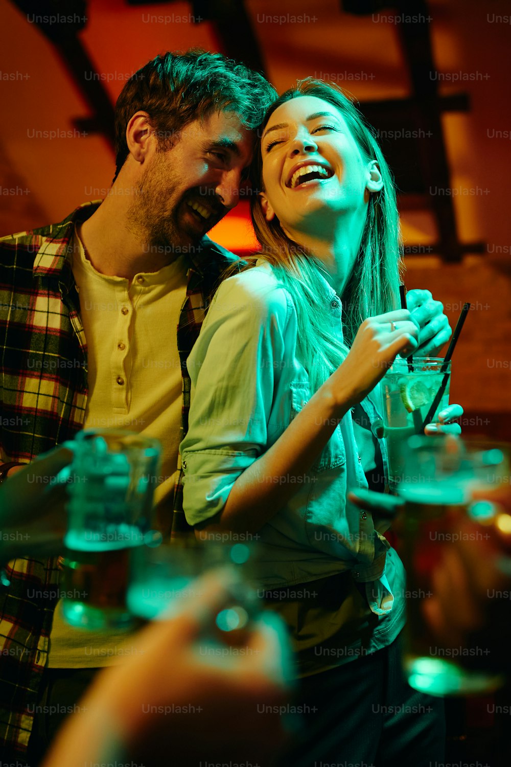 Junges, sorgloses Paar, das Spaß während des nächtlichen Dates in einer Bar hat.