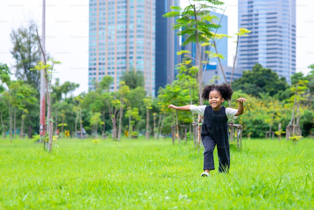 Glückliche gemischtrassige Familie im Park. Entzückendes Kind Mädchen läuft und spielt im öffentlichen Park. Lächelnde kleine Tochter genießen und Spaß Outdoor-Lifestyle-Aktivität Sommerwochenende Ferien.
