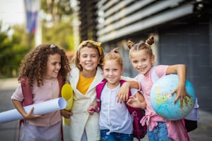 Retrato de cuatro colegialas de pie afuera.