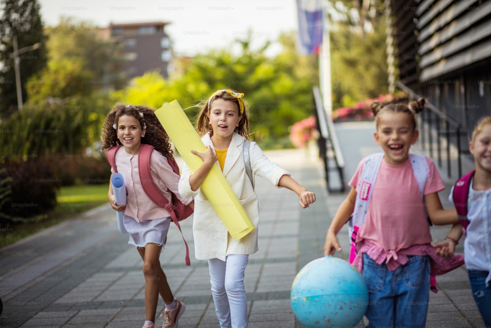 Crianças sorridentes voltando para casa depois da escola. As meninas da escola correndo no pátio da escola.