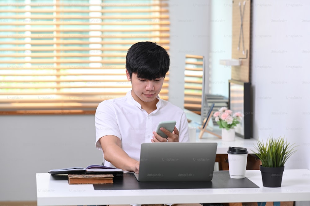 Young man sitting in comfortable office and using smart phone.