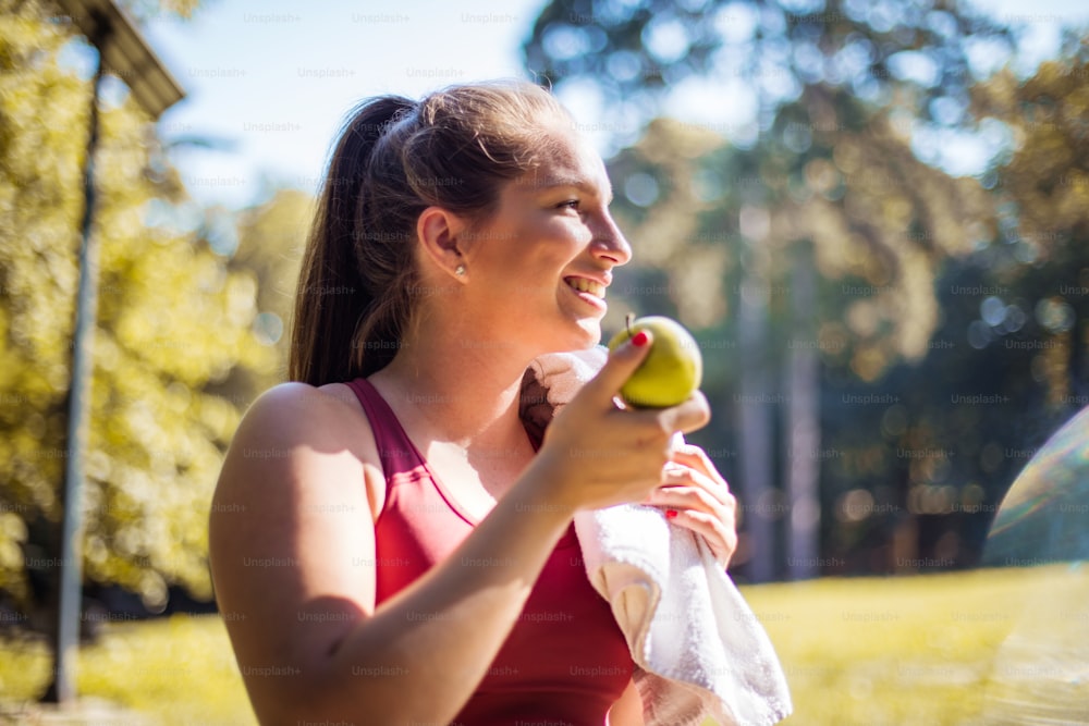 Mulher no parque comendo maçã.