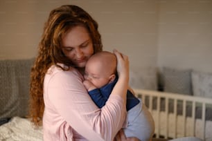 Adorable baby boy bonding with his mother in the bedroom while she holds him in her arms