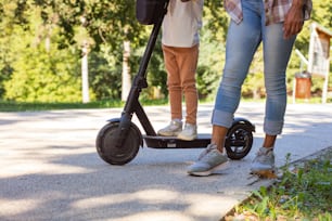 Mom and daughter in nature with e-scooter. Close up.