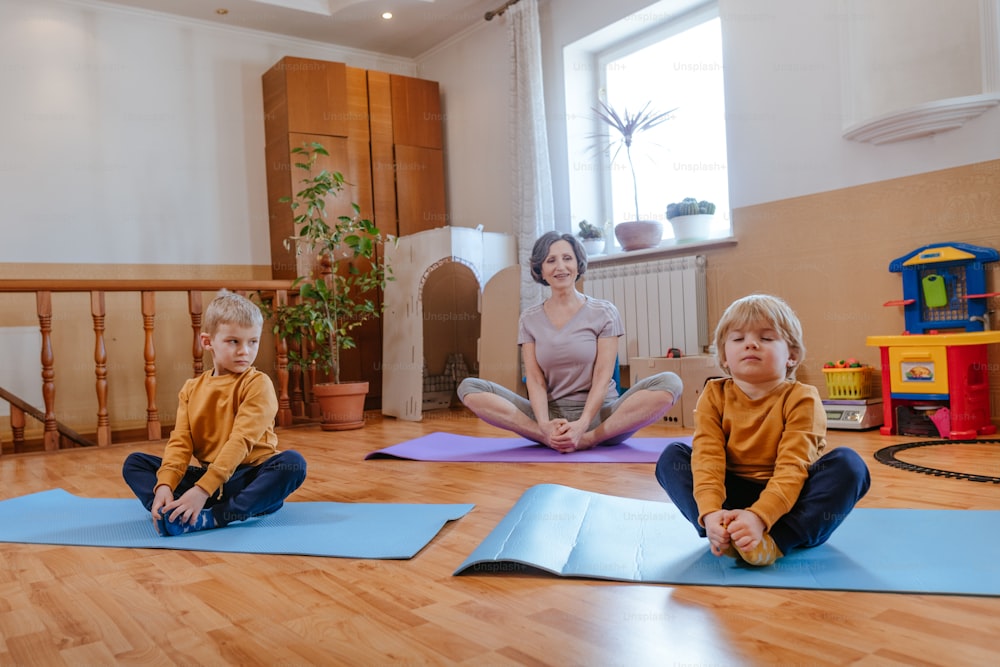 Two boys doing yoga with their grandmother in the kids room. Selective focus.