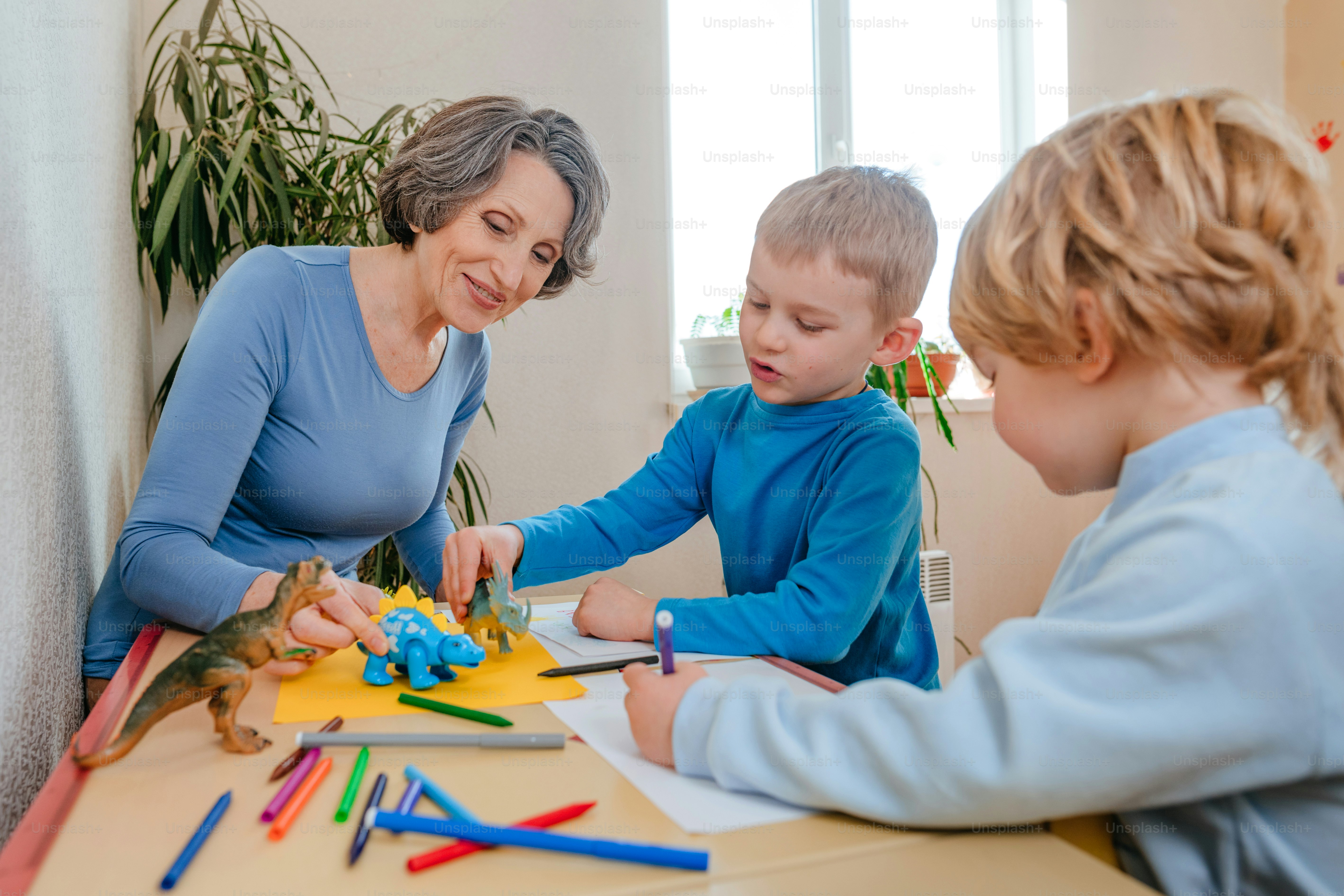 Garçons jouant avec sa grand-mère avec des jouets de dinosaures dans la chambre des enfants. Mise au point sélective.