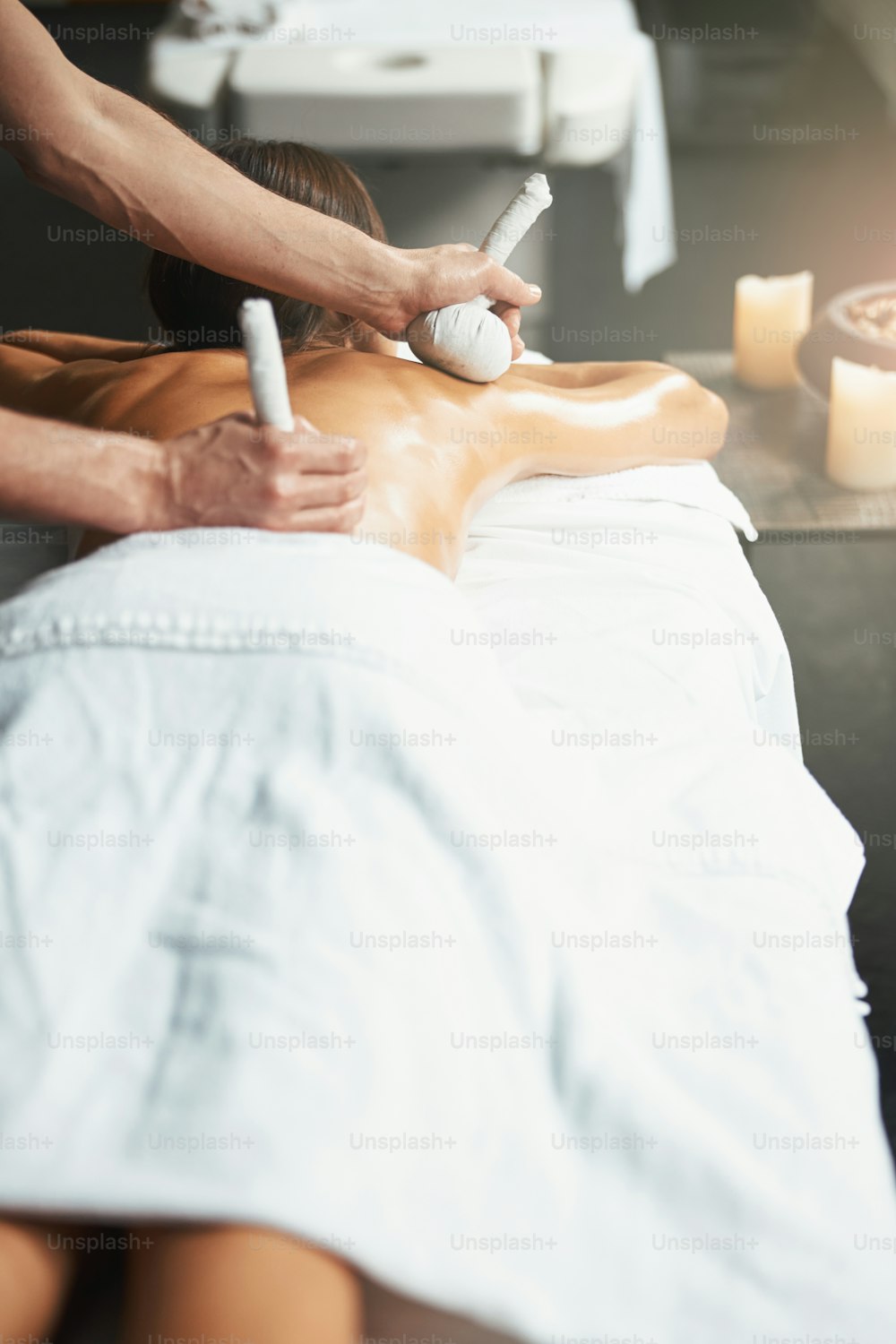 Waist up back view portrait of charming elegant female on massage table getting new massage technique in health center