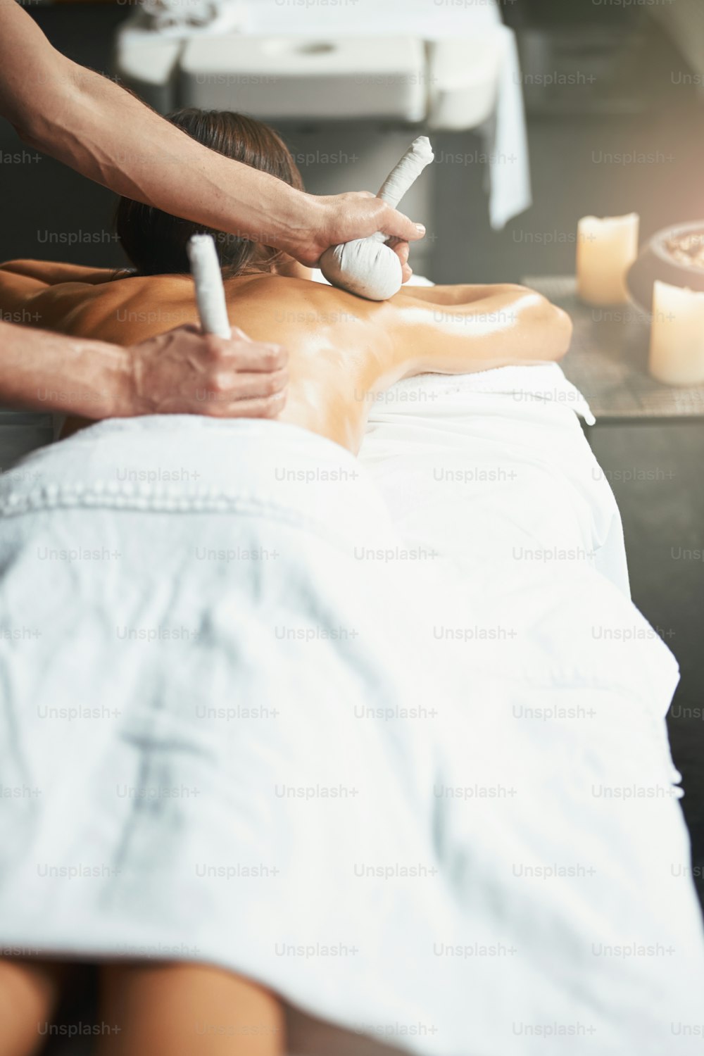 Retrato de la vista trasera de cintura hacia arriba de una mujer elegante encantadora en la mesa de masaje que obtiene una nueva técnica de masaje en el centro de salud