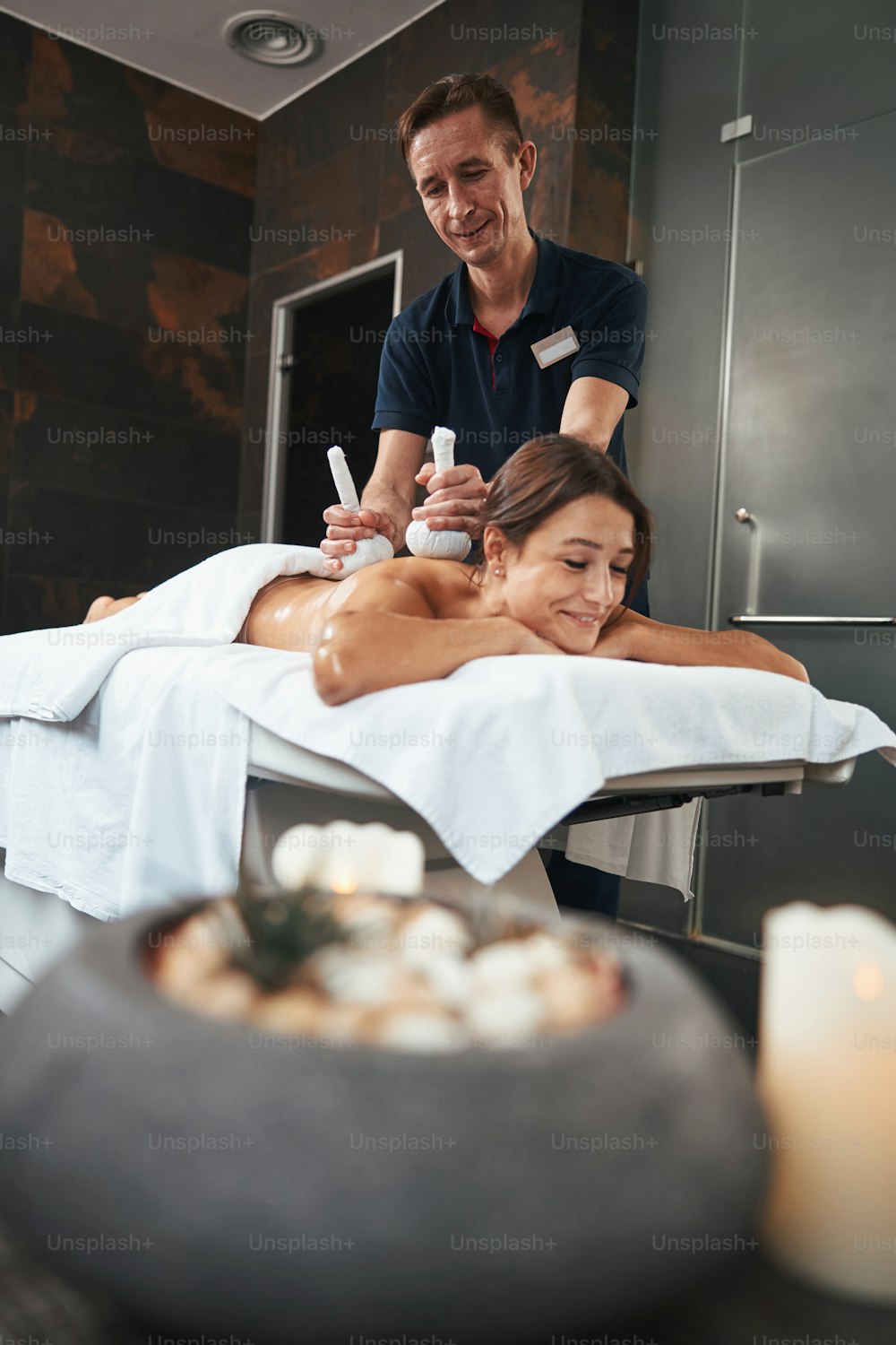 Waist up side view portrait of pretty peaceful lady lying on massage table while getting new massage technique with white special tools in medicine center