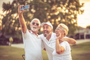 Senior golfers using phone and taking self portrait.