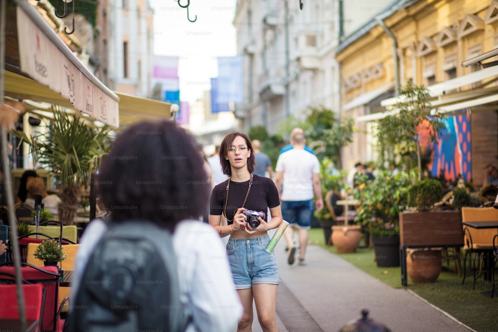 Photographer. Two tourist women on street. Focus on background,