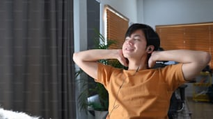 Lässiger junger asiatischer Mann, der sich zu Hause auf einem Stuhl entspannt.