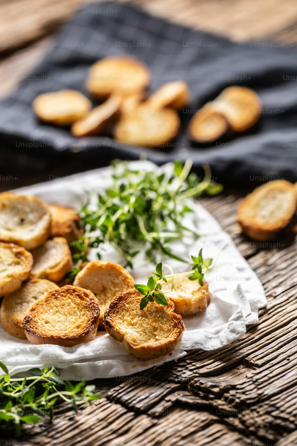 Kleine runde salzige Mini-Backbrötchen mit herrlich knusprigem Geschmack und goldlicher Farbe aus gebackenem Brot, serviert im Papier oder Geschirrtuch mit Thymian.