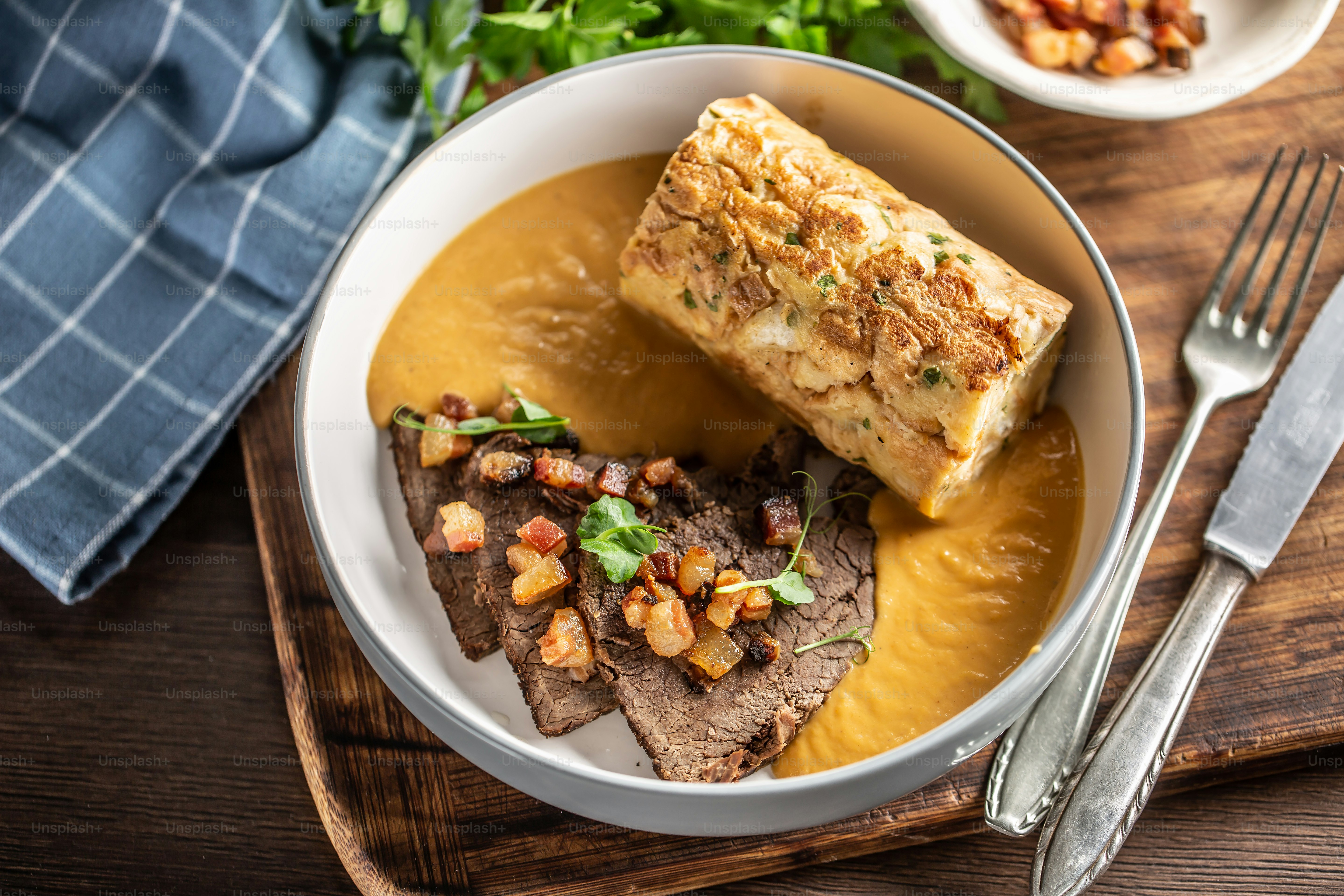 Top view of a svickova dish served on a plate, wooden tray, next to cutlery.