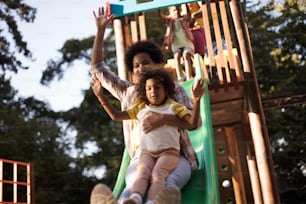 Playful family in the playground. African American mom playing with child on playground.