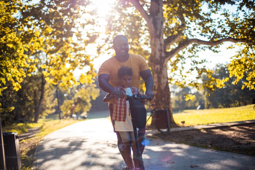 Afroamerikanischer Vater fährt Elektroroller.