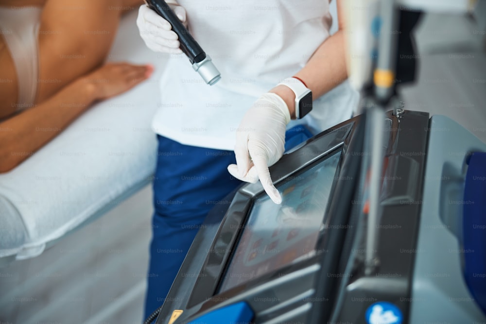 Foto ritagliata di un'estetista professionista che prepara una giovane paziente per una depilazione laser