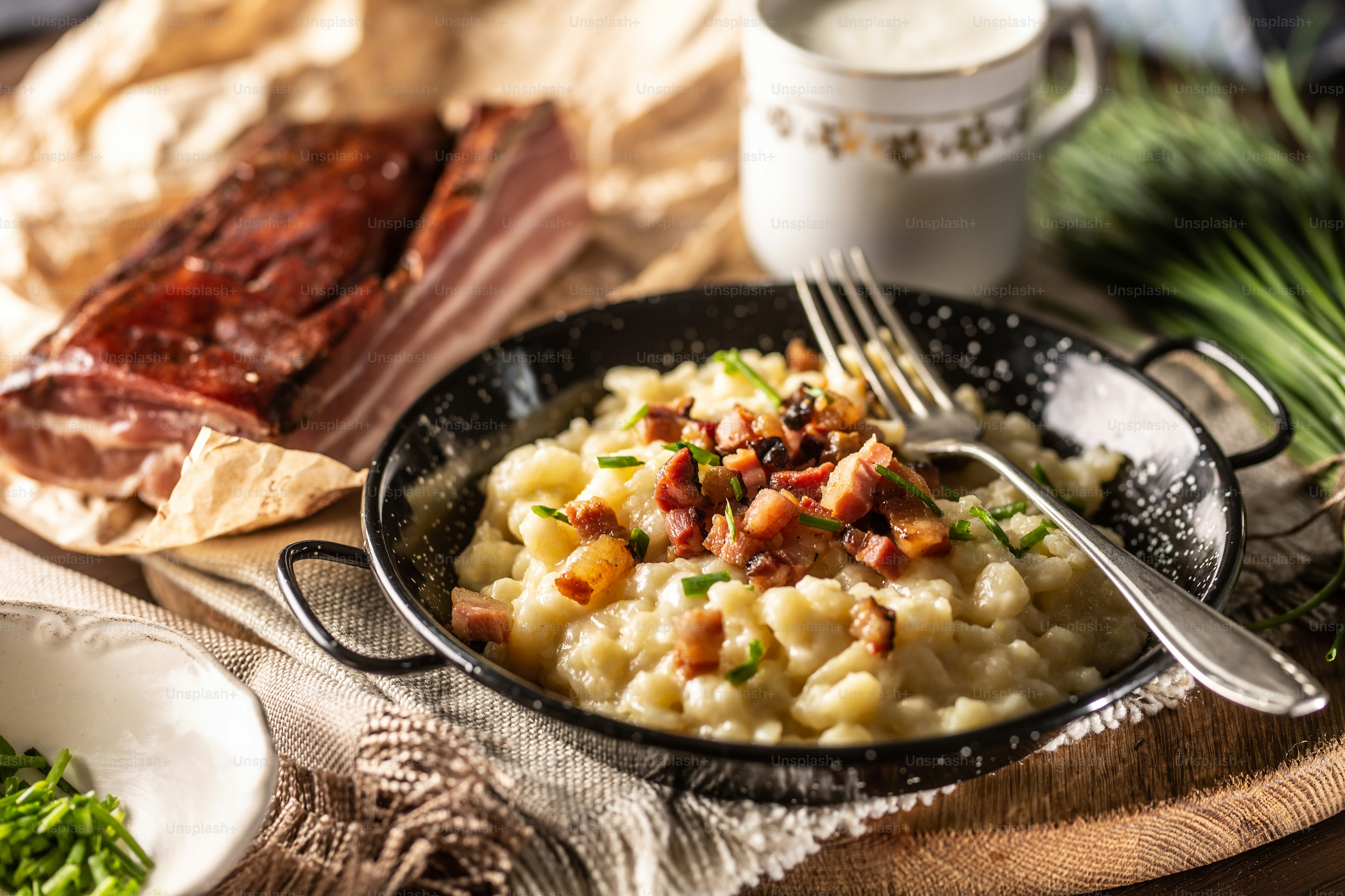 Slovak national dish bryndzove halushky served next to bacon and a gcup of milk.