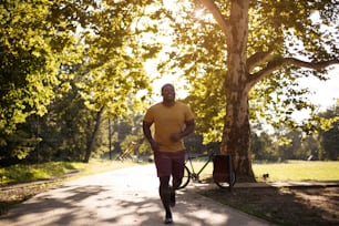 Time for exercise.  African American man running trough park.