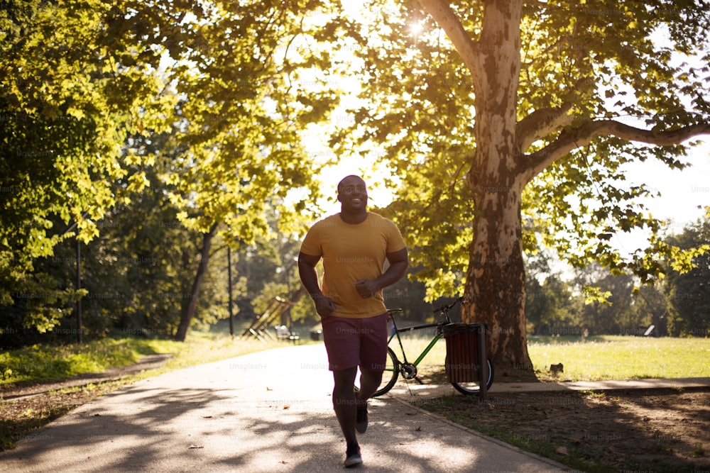 Tiempo para hacer ejercicio.  Hombre afroamericano corriendo por el parque.