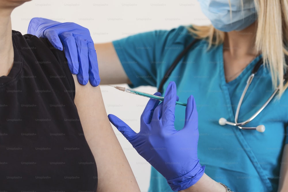 Femme médecin ou infirmière administrant une injection ou un vaccin à l’épaule d’un patient. Vaccination et prévention contre la grippe ou la pandémie virale. Concept de vaccination