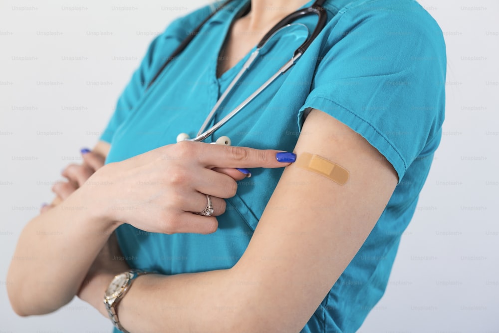 Young woman octor with adhesive bandage on her arm after Coronavirus vaccine. First aid. Medical, pharmacy and healthcare concept.