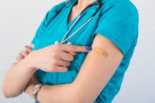 Young woman octor with adhesive bandage on her arm after Coronavirus vaccine. First aid. Medical, pharmacy and healthcare concept.