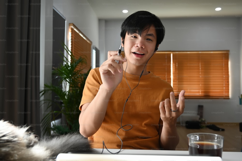 Young asian man wearing earphone and videoconference with his business partner.