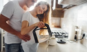 Young couple at morning together standing on the modern kitchen.