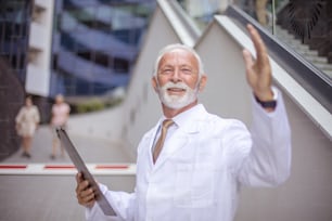 Senior doctor standing on street and writing on document.