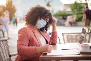 Work at café.  Business woman with protective face mask working in café.