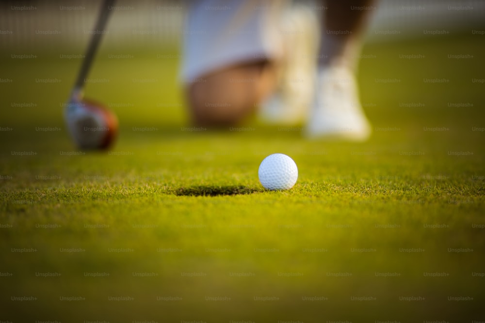 Senior man playing a golf. Close up of golf ball on the grass.