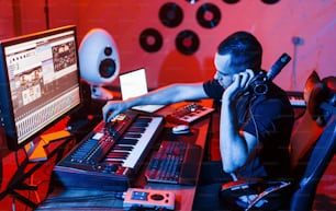 Giovane ingegnere del suono che lavora e mixa musica all'interno dello studio.
