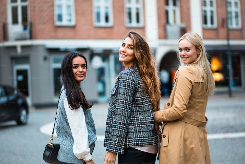 Retrato de três mulheres em pé na rua e olhando para a câmera.